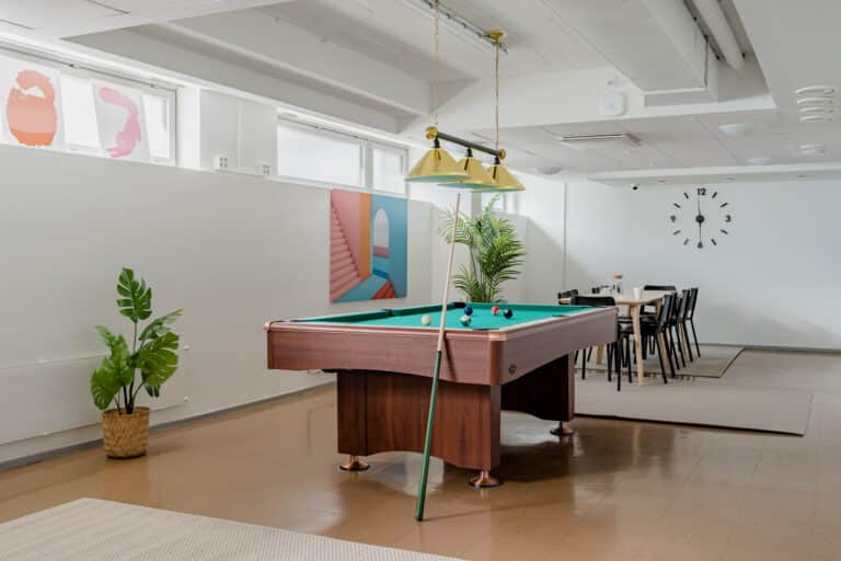 Spacious club room with a billiards table and dining area, offering comfortable shared spaces for students living in student housing