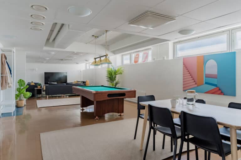 Student housing club room featuring a billiards table, sofa lounge, and TV, ideal for relaxation and socializing among students